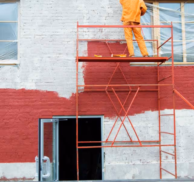 Façade en brique repeinte en rouge depuis un échafaudage, ravalement par ISL Artisan Peintre