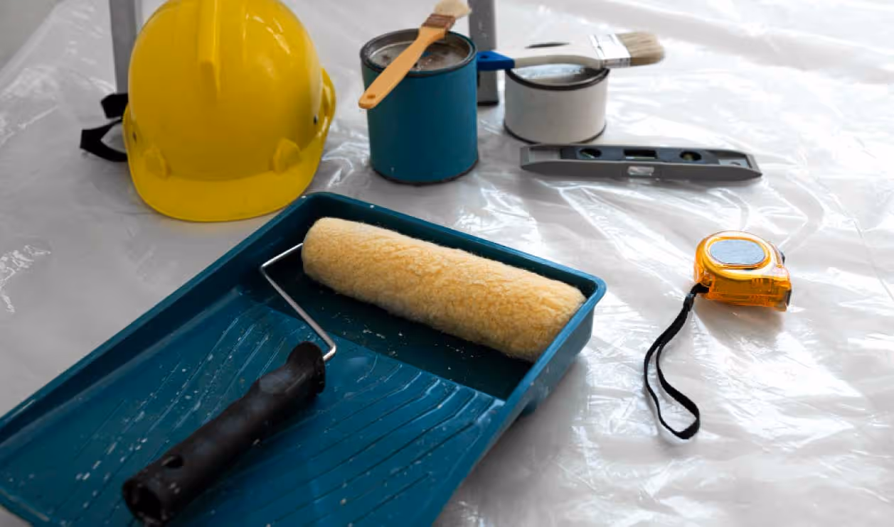Rouleau, bac à peinture et matériel de protection sur une bâche, sur un chantier de peinture à Schiltigheim